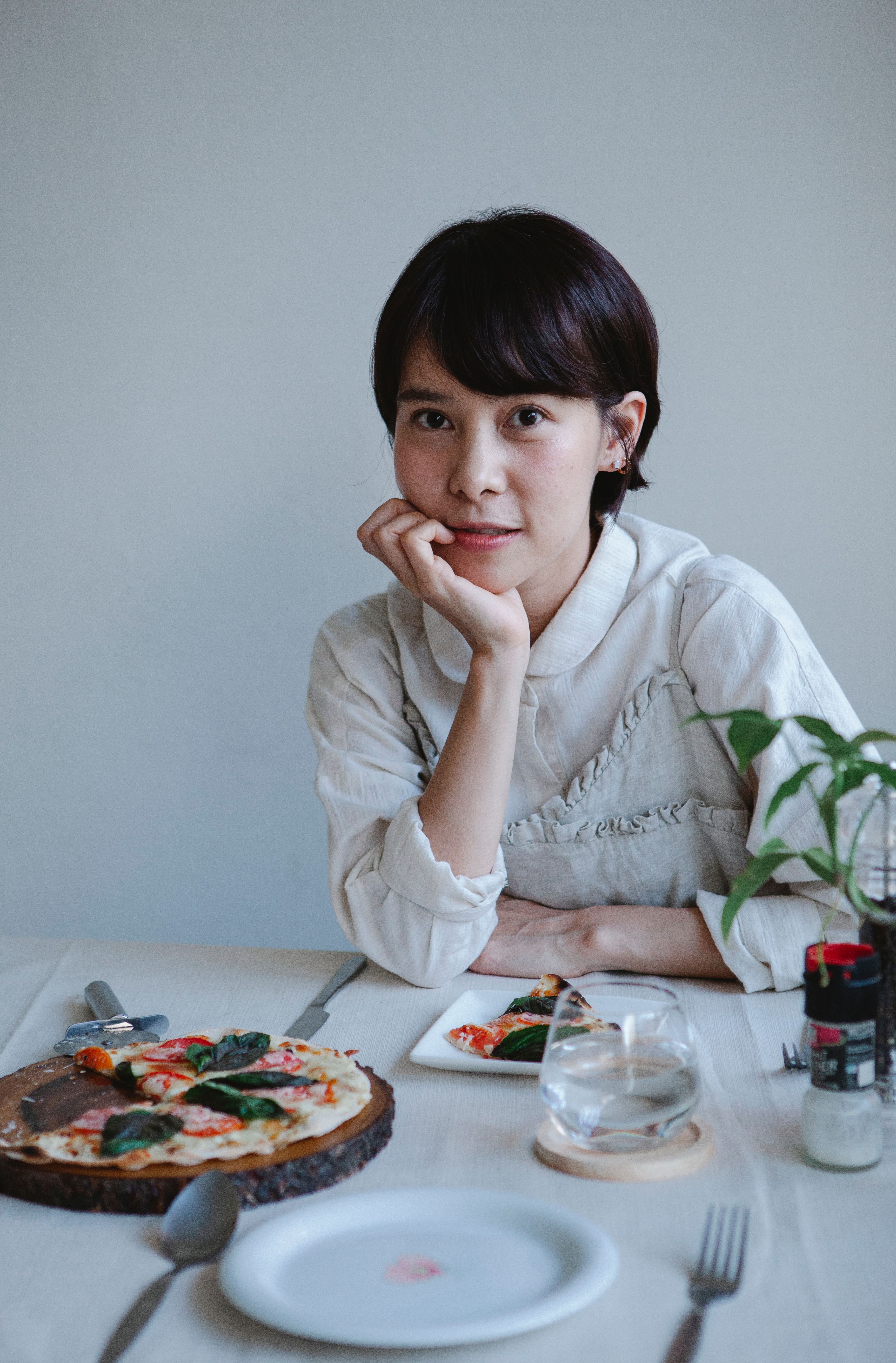 Casual dining scene with an Asian woman enjoying pizza at a set table indoors.