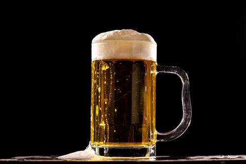Free A detailed shot of a cold beer glass with frothy top against a black background. Stock Photo