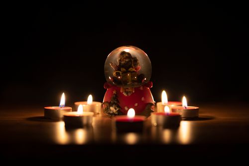 Free A cozy scene featuring a Christmas snow globe surrounded by candlelight, creating a warm holiday vibe. Stock Photo