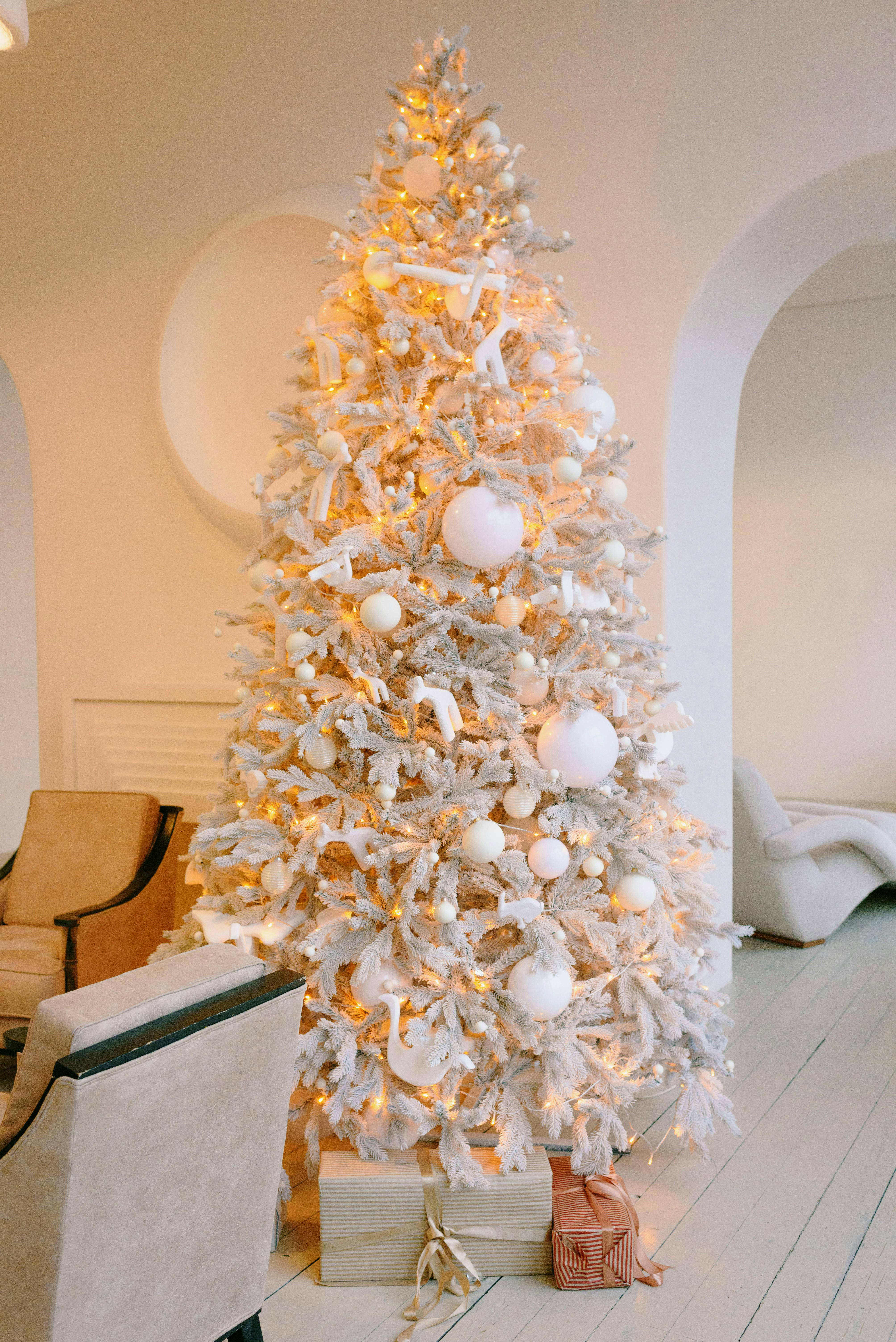 A beautifully decorated white Christmas tree in a cozy modern living room setting.