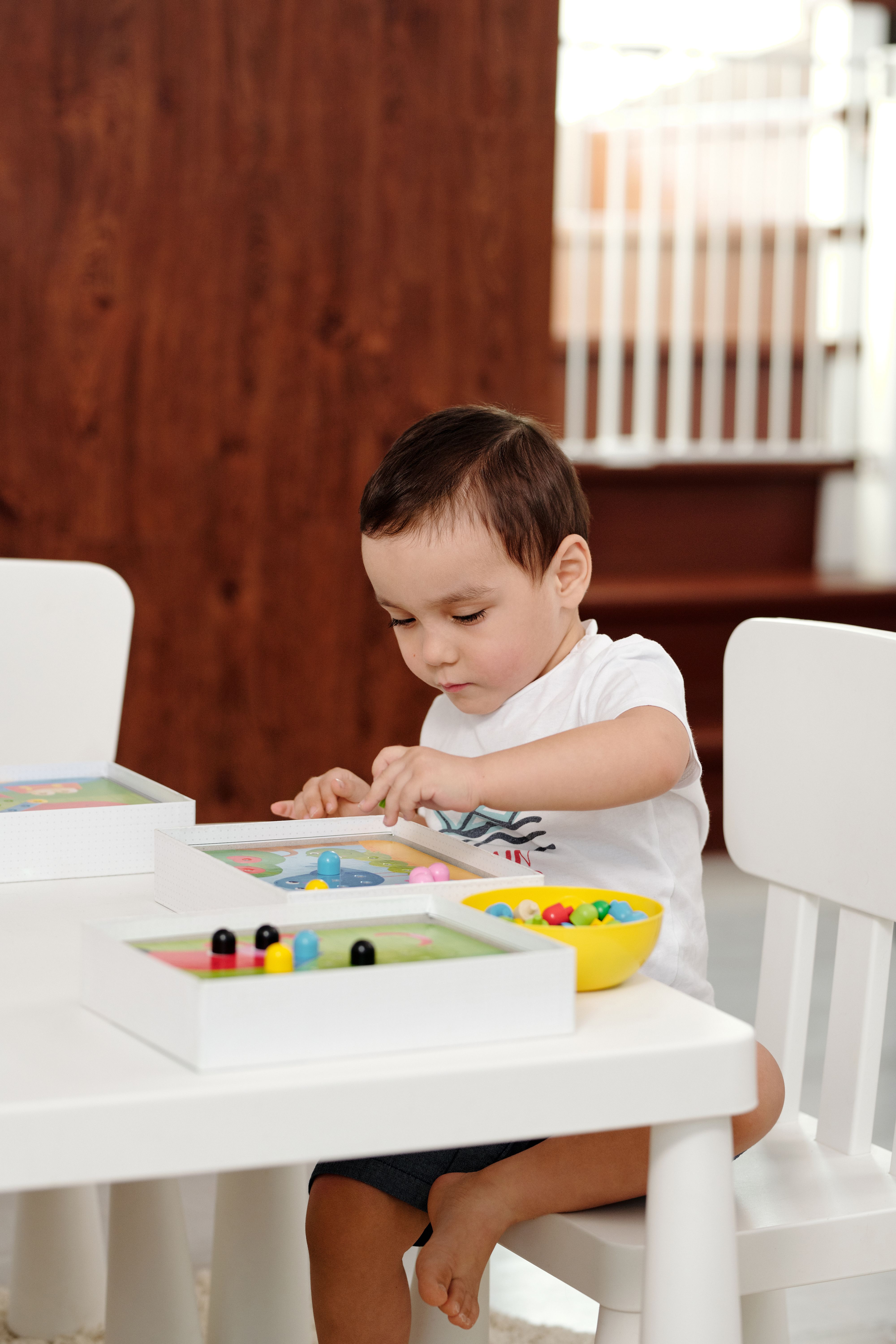 Fotomural Niño pequeño sentado a la mesa, concentrado en bloques de juguete coloridos, fomentando la creatividad y la concentración.