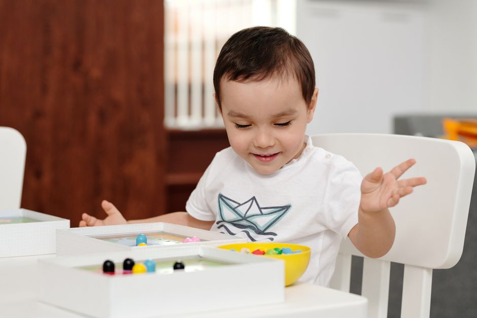 Photo by Jep Gambardella on Pexels A cheerful child engaged in play with colorful beads indoors, expressing delight and curiosity. - Photo by Jep Gambardella on Pexels