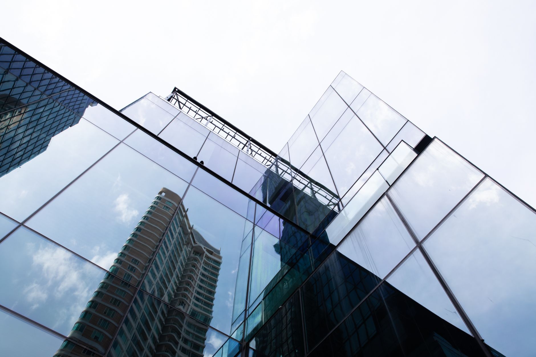 Modern skyscraper with glass facade reflecting the Bangkok cityscape.