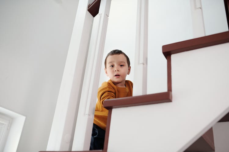 An Innocent Little Boy Going Up The Stairs While Looking At The Camera