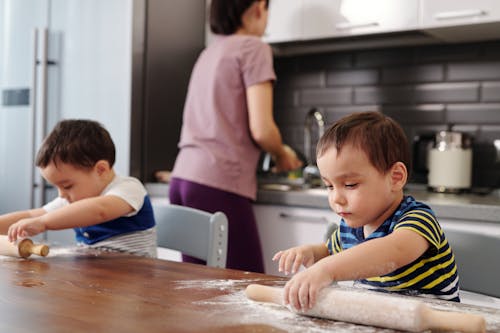 Two Little Boys Helping Their Mother in the Kitchen and Using a Rolling Pin 