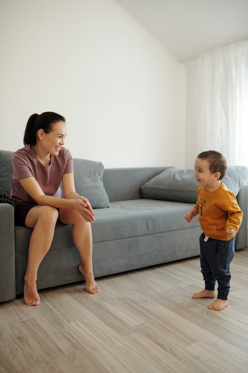 Free Mother Sitting on a Couch while Looking at his Son Standing  Stock Photo