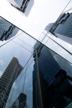 Modern glass skyscrapers reflect each other under a bright sky in Bangkok, Thailand.