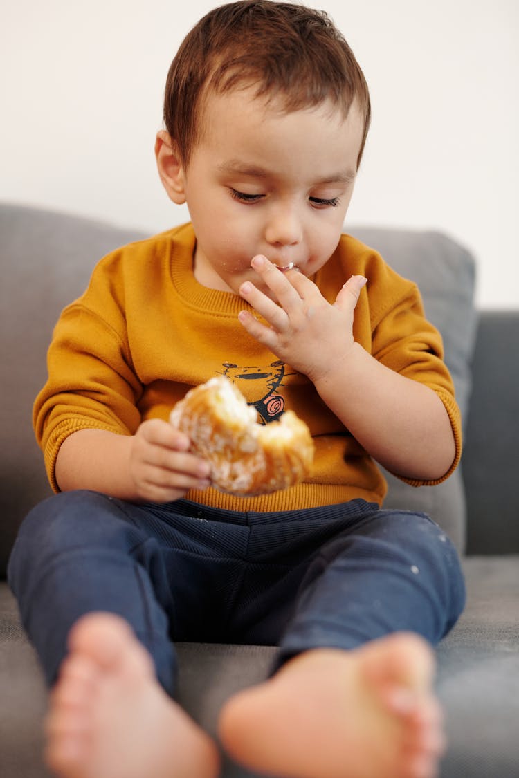 Boy In Yellow Sweater Eating Bread