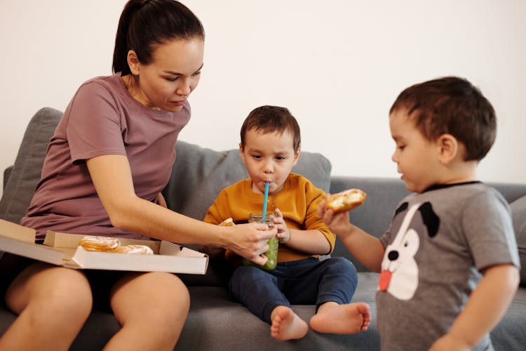 Boy Sitting On Sofa Drinking From A Straw