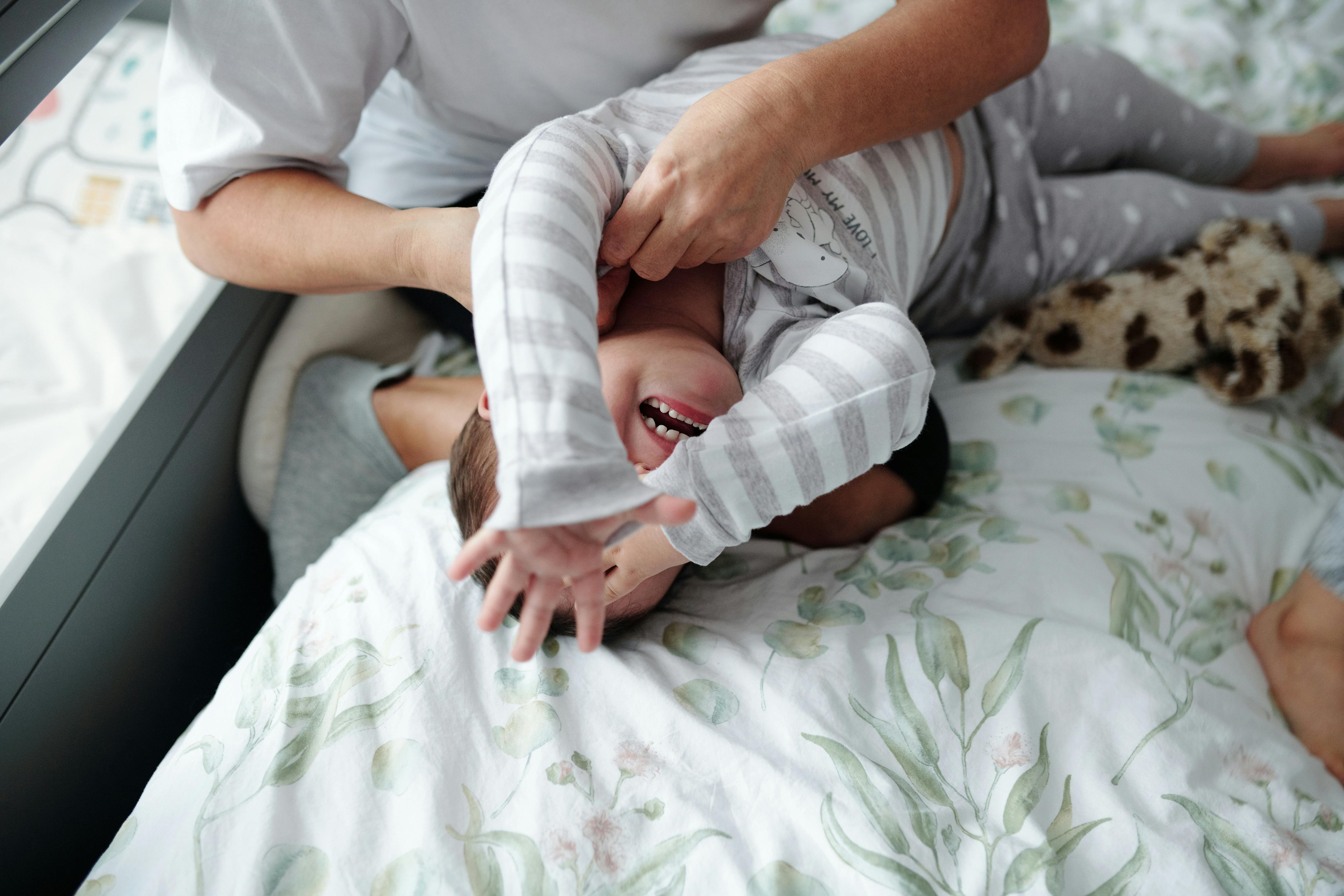 mother holding her baby on a bed