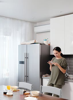 Adult woman using smartphone in a contemporary kitchen setting.