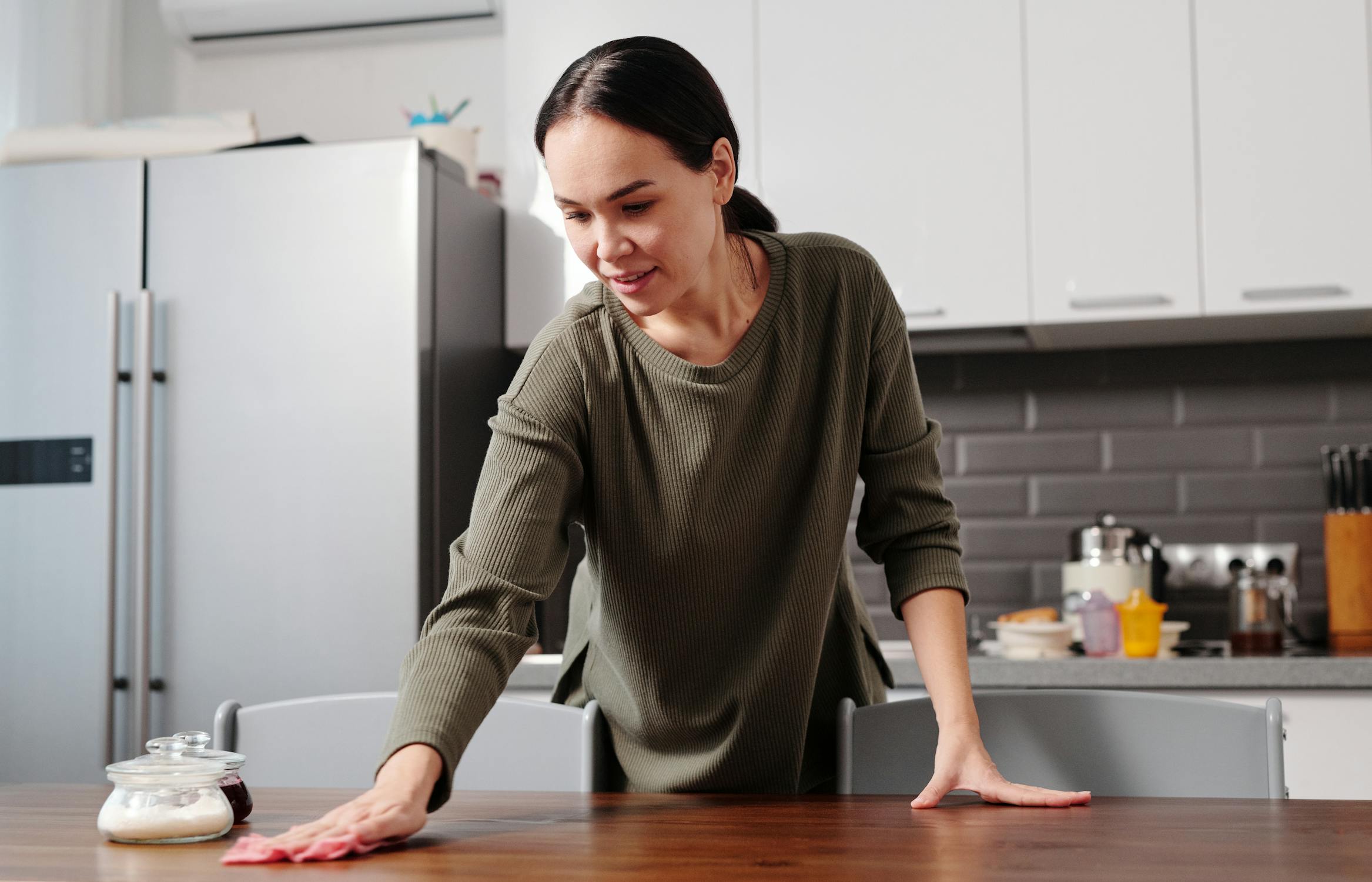 Woman wiping table with European vs American fridges
