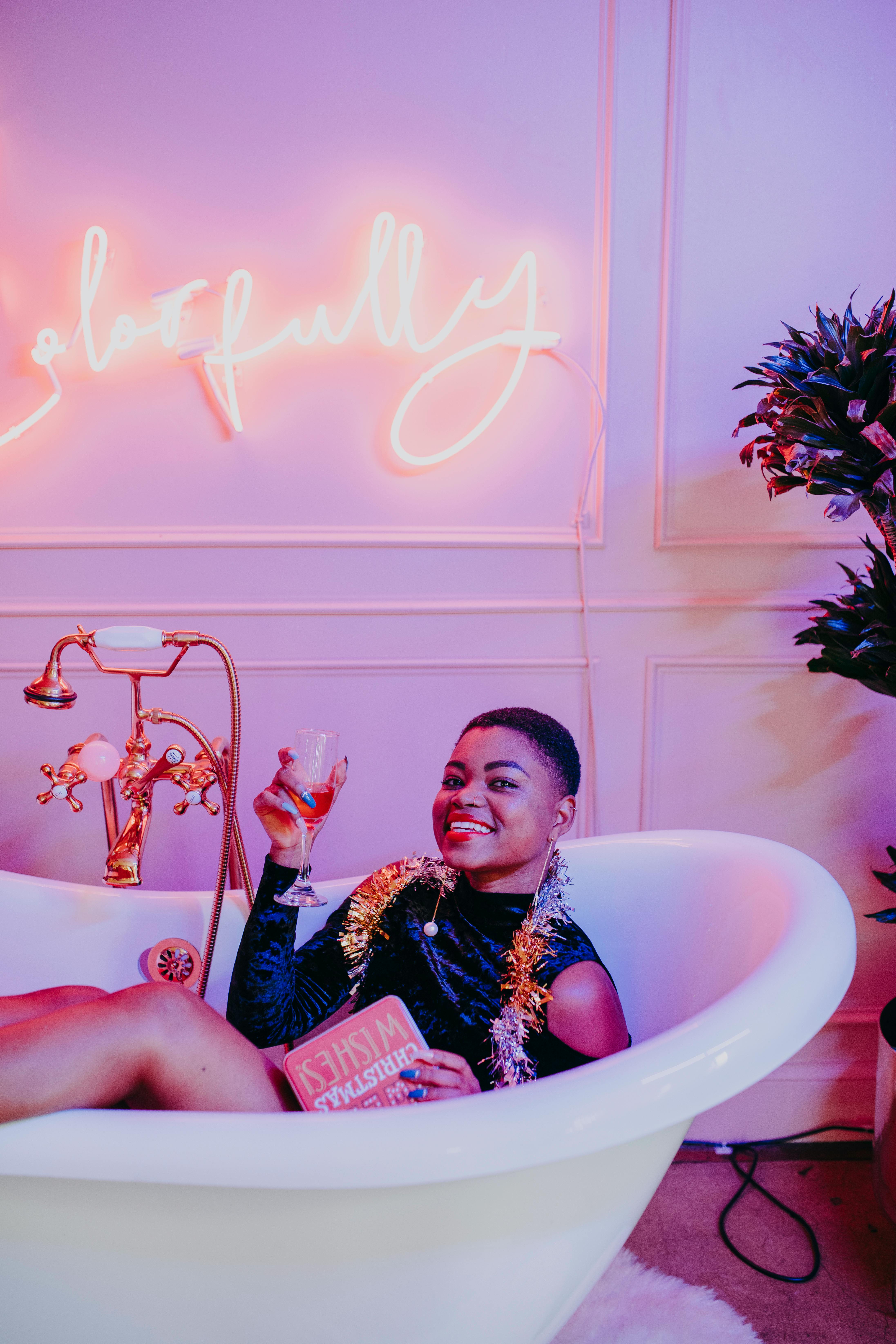 woman in white bathtub holding book