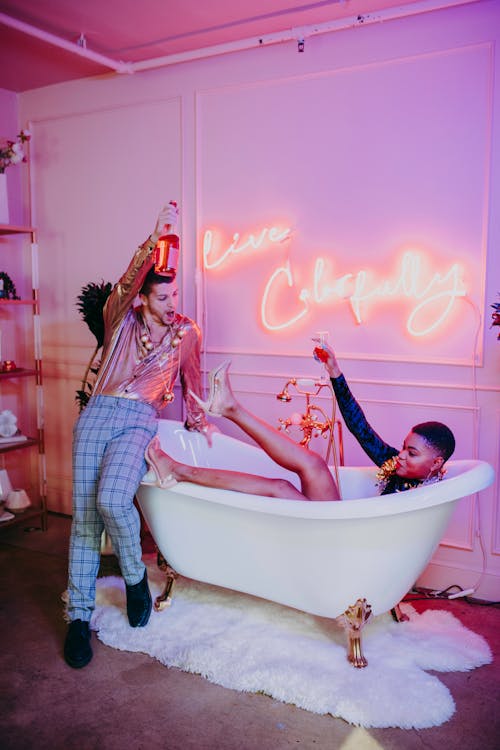 Two Stylish People hanging out on a Bathtub 