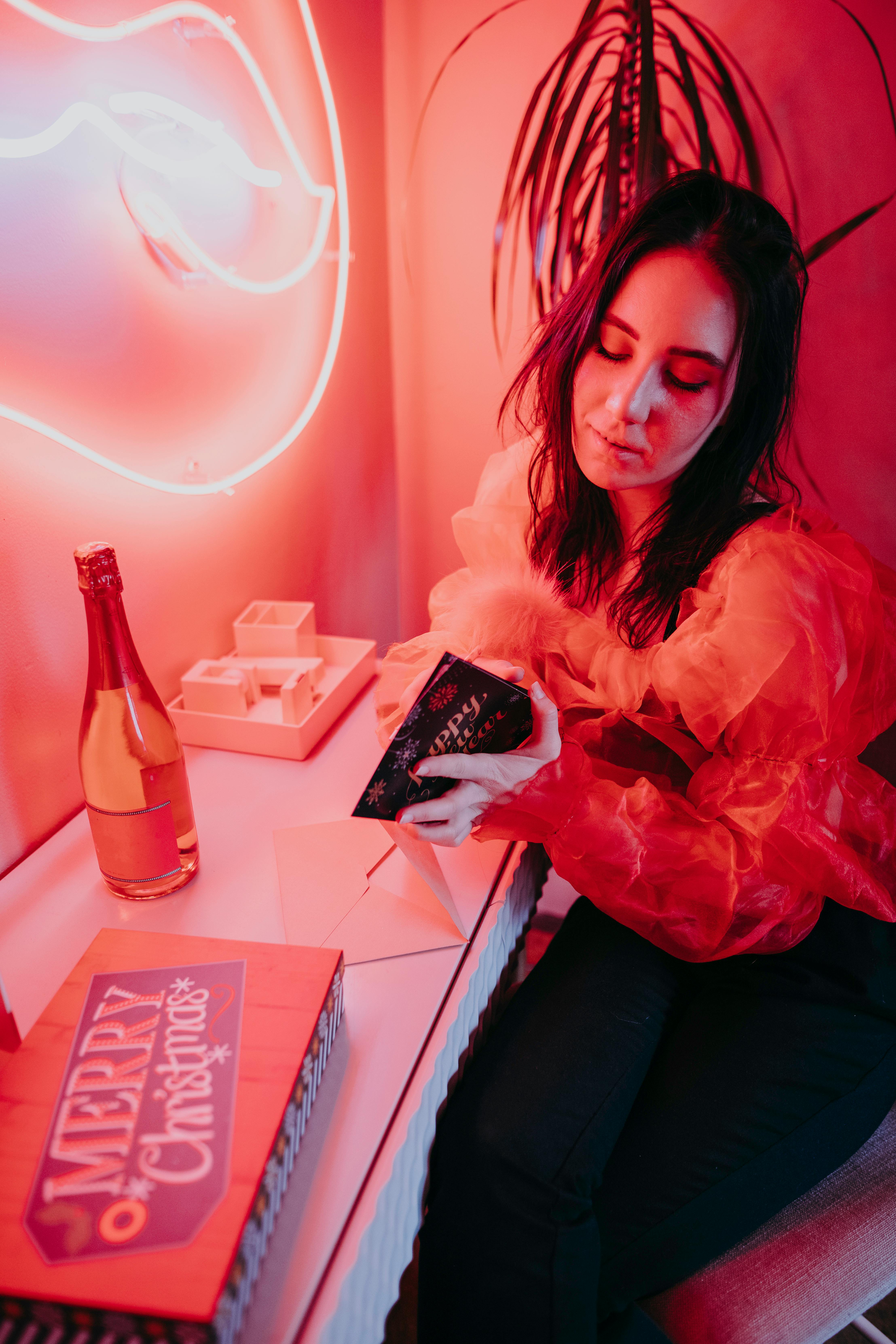 woman in pink long sleeve shirt sitting beside table with coca cola bottle