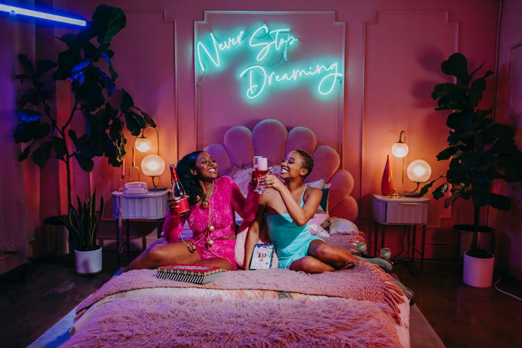 Women Sitting On Bed Having A Toast