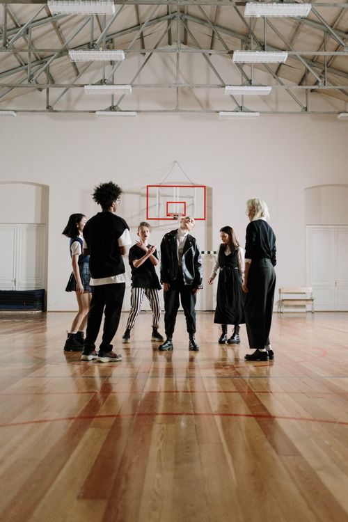 Free A diverse group of teenagers standing in a sports hall, engaging in discussion. Stock Photo