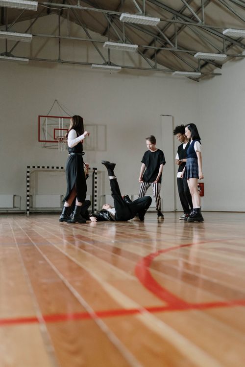 Free A group of teenagers dancing and socializing in a spacious indoor sports hall. Stock Photo