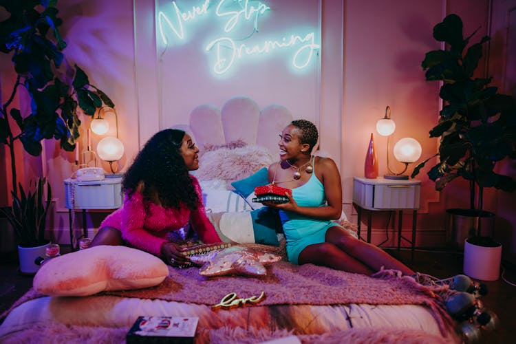 A Two Women Having Conversation On The Bed