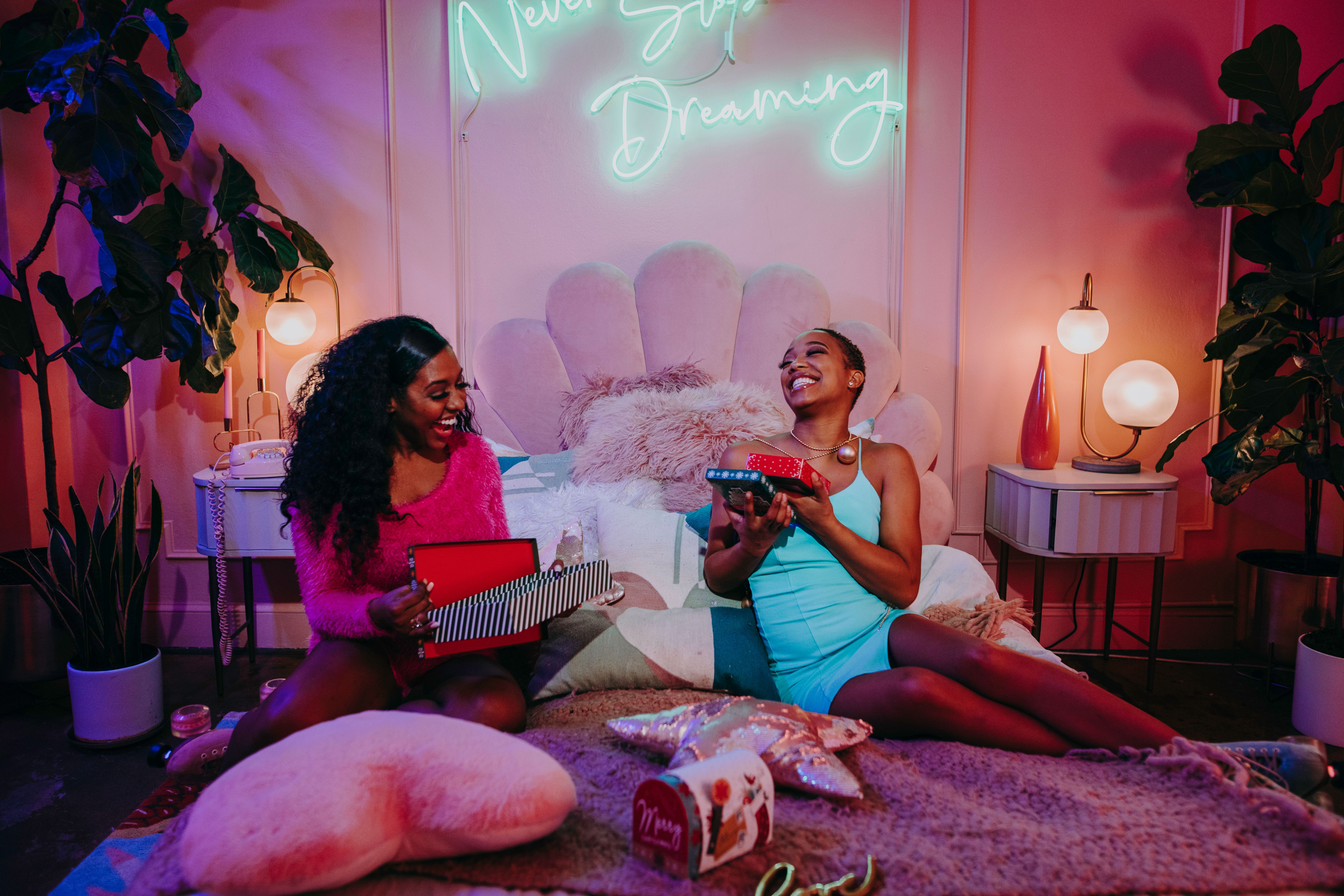 Joyful indoor holiday celebration with women exchanging gifts in a cozy setting.