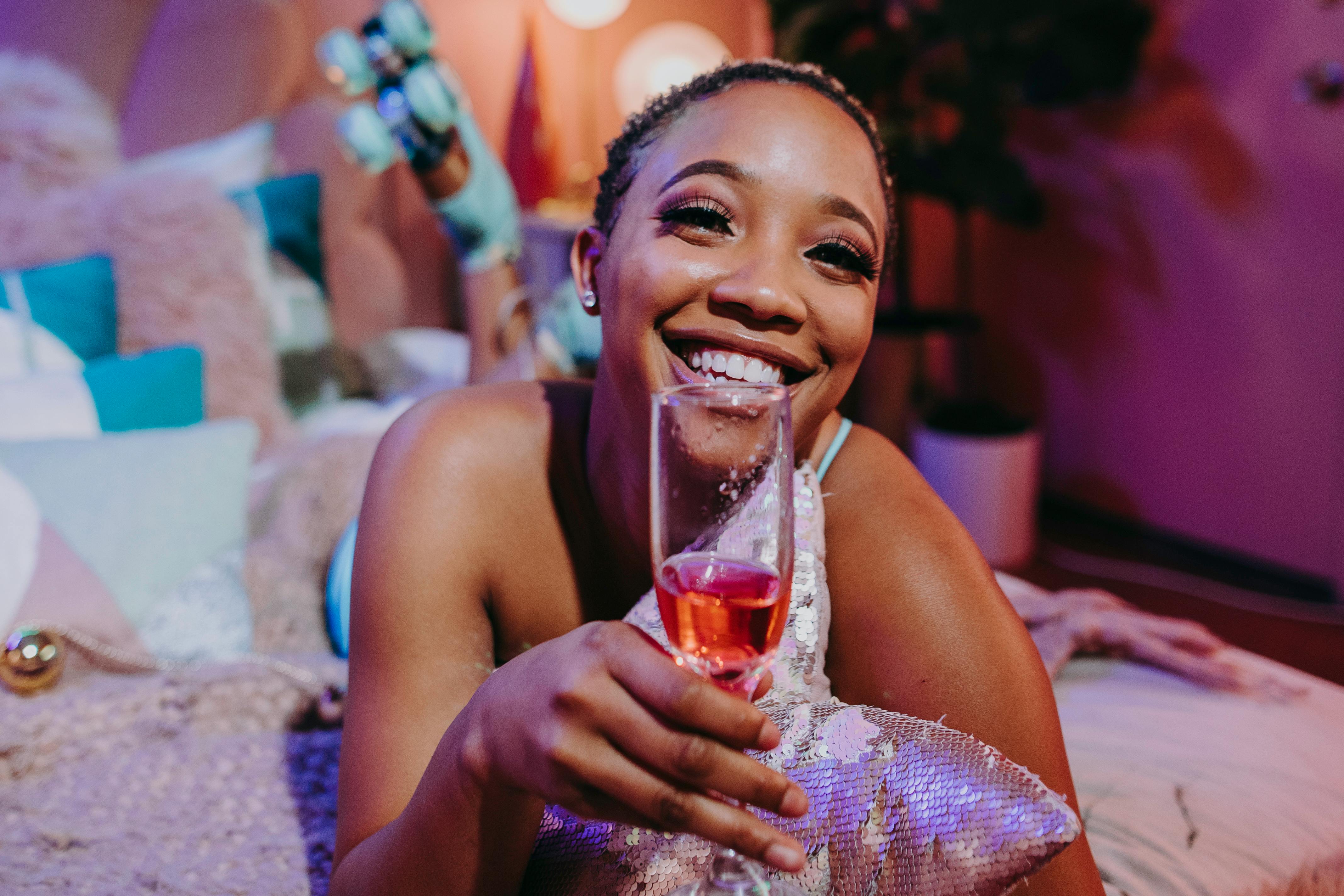 woman in blue tank top holding clear drinking glass