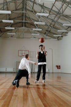 Two men playing basketball indoors, capturing a dynamic sporting moment.