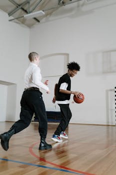 Two young men engaging in a friendly basketball game indoors, showcasing athletic skills and teamwork.