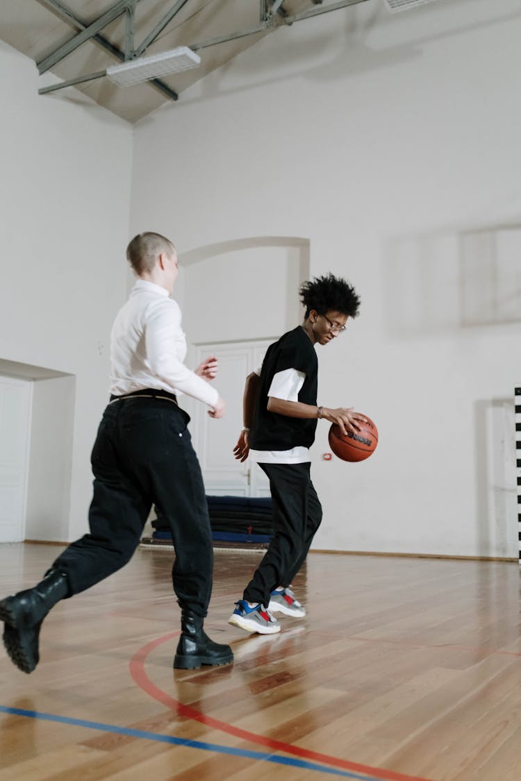 Young Men Playing Basketball In A School Gym 