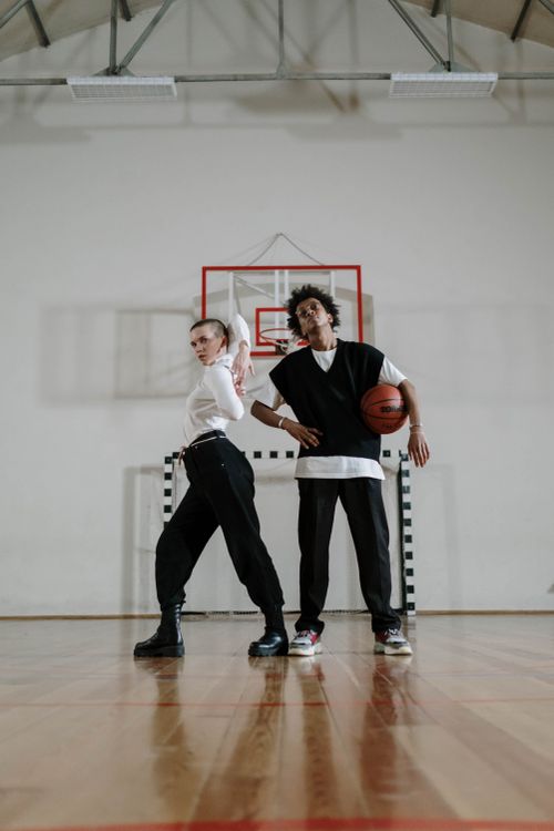 Free Two teenagers posing with basketball on an indoor court, embracing active lifestyle. Stock Photo