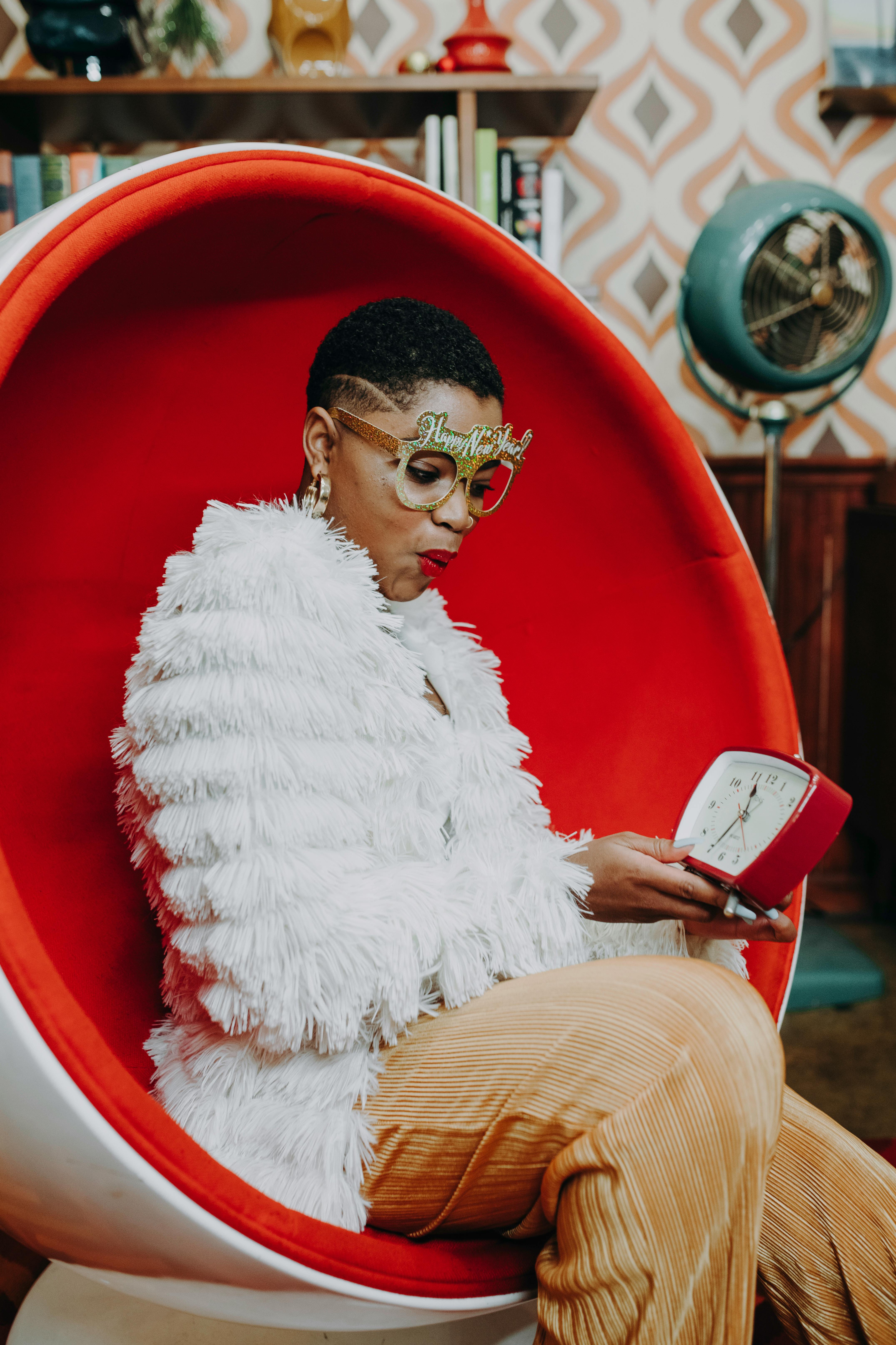 man in white fur coat sitting on red plastic chair