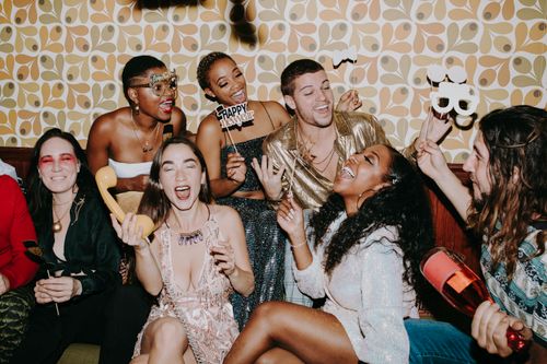Free A diverse group of friends joyfully celebrating New Year's Eve indoors, capturing festive fun. Stock Photo