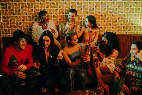 Free A joyful group of diverse friends celebrating at a holiday party with drinks and festive decorations. Stock Photo