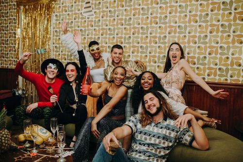 Free Joyful group of friends celebrating New Year's Eve with drinks and festive attire indoors. Stock Photo