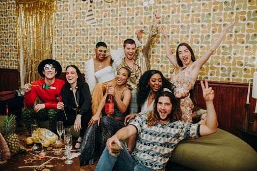 Free A joyful group of friends celebrating indoors with festive drinks and party attire. Stock Photo