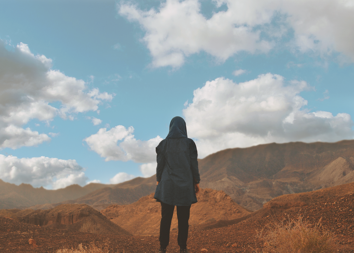 A lone figure looking out over a high mountain ridge.