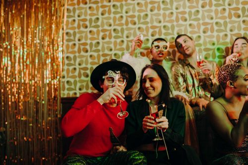 Free Group of friends enjoying a vibrant New Year's party indoors with glasses of champagne. Stock Photo