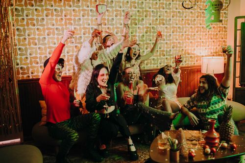 Free A lively group of friends celebrating with drinks and laughter in a cozy indoor setting. Stock Photo