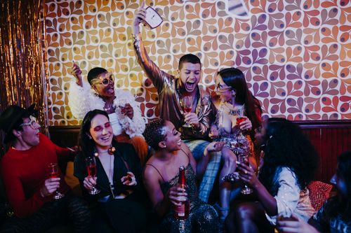 Free Group of diverse friends enjoying a lively indoor retro-themed celebration. Stock Photo
