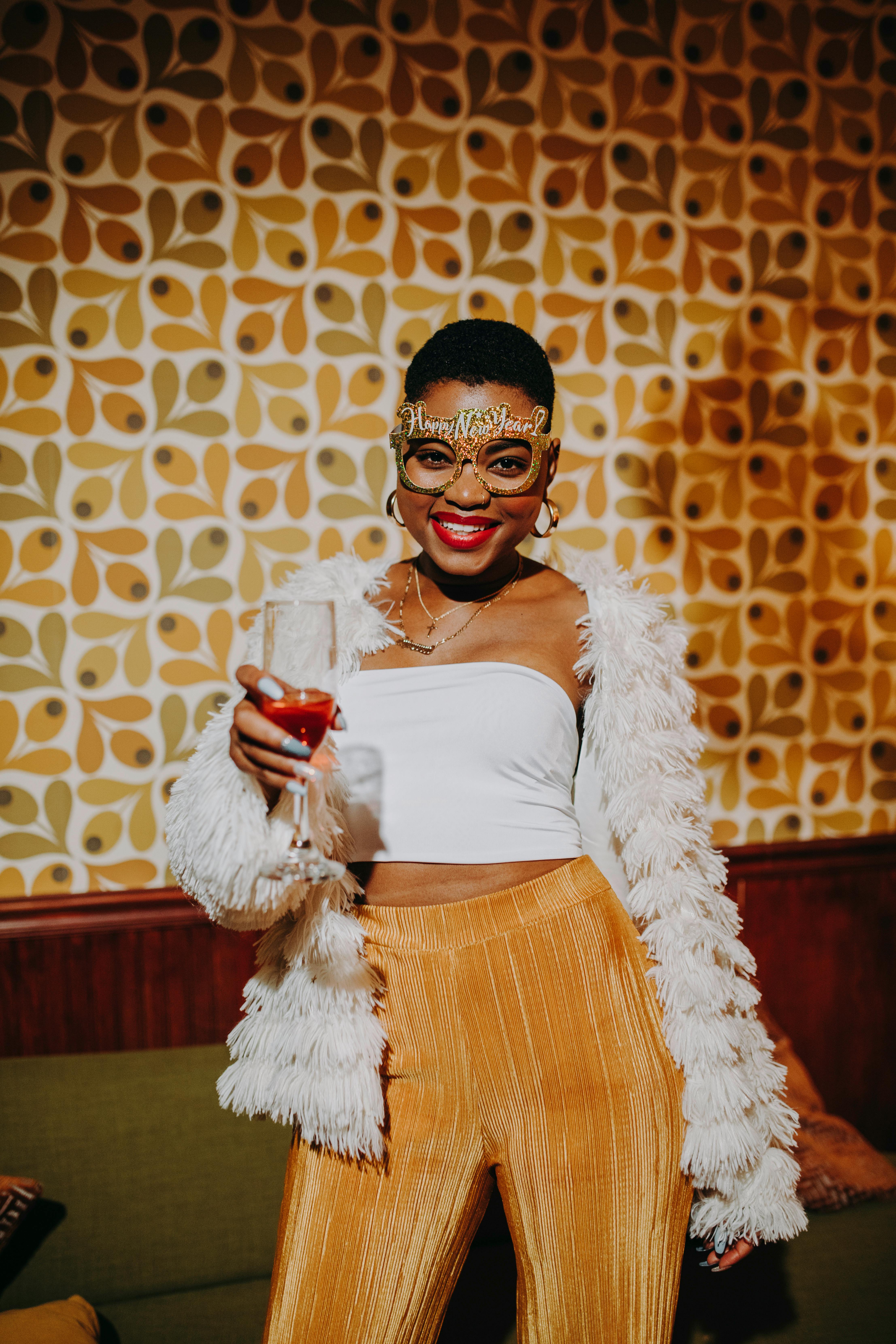 Stylish woman celebrating New Year's Eve with a champagne toast in a festive setting.