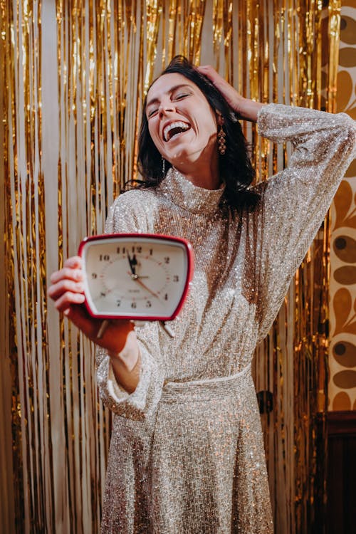 Woman Laughing While Holding an Alarm Clock