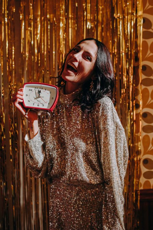 Free Woman holding clock, ready for New Year's countdown celebration in festive outfit. Stock Photo
