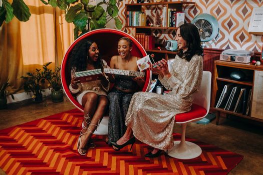 Three women joyfully unwrapping gifts in a stylish vintage indoor setting.