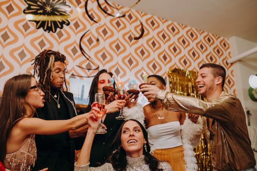 Joyful friends toasting with drinks at a vibrant retro-themed party indoors.