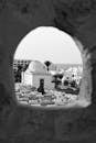 一张黑白照片，透过拱门拍摄的清真寺和建筑物