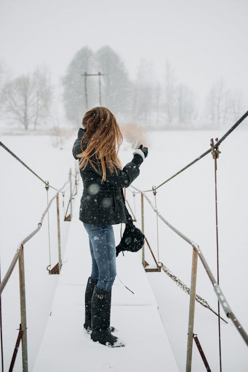 Woman Wearing Jacket Standing on Footbridge