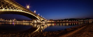 城市灯光下，一座明亮的桥梁倒映在平静的河流上，构成令人惊叹的夜间景观