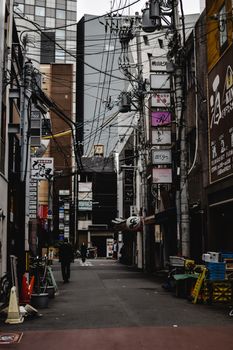 A bustling alleyway in Osaka, Japan, featuring vibrant signage and urban architecture.