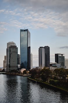 A stunning view of modern skyscrapers along Osaka's riverfront under a cloudy sky, capturing the city's vibrant architecture.