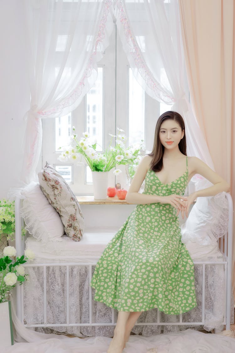 Beautiful Woman In A Dress Sitting In A Neat Bedroom 