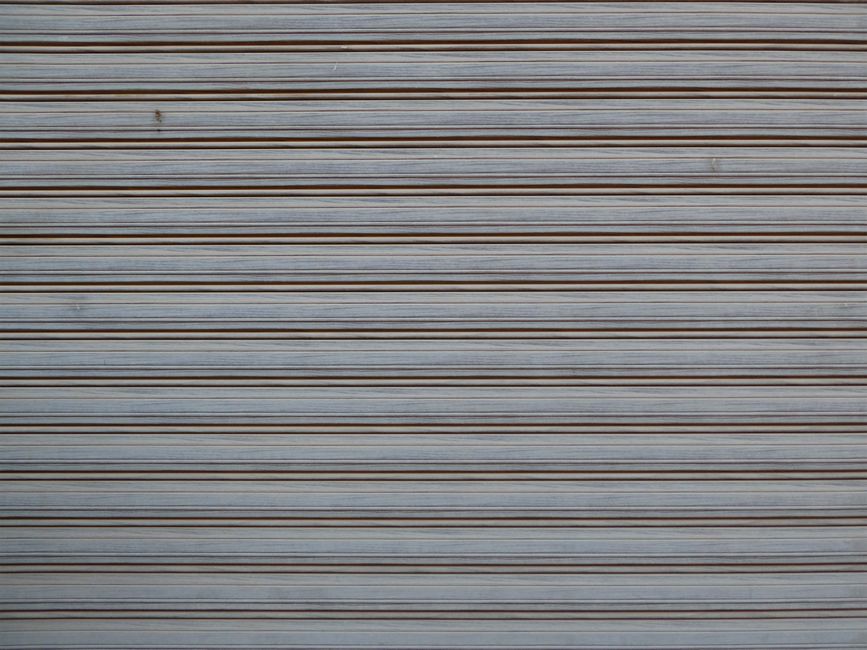 Close-up of a gray metal shutter with repeated horizontal lines, creating a striped pattern.